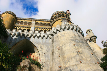 Low angle view of Pena National Palace, with its imposing walls and original colorful architecture. It's overlooking the Sintra village, near Lisbon. © M.Scarselletta