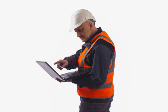 Computer foreman in safety helmet. Concept builder with laptop. Builder is standing and holding laptop. Builder is considering hundred something on  laptop. Construction worker on light background