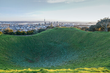 Light frost settles in shadow of volcanic crater on Mount Eden, Auckland city skyline beyond.
