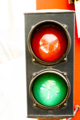 Traffic light with two lights, red and green, on a red pillar that indicates advance or stop. Road...