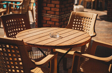 a table in a street cafe with an ashtray and four plastic chairs on a sunny day