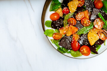 top view of exquisite salad of beetroot, orange, cherry tomato and arugula with olive oil
