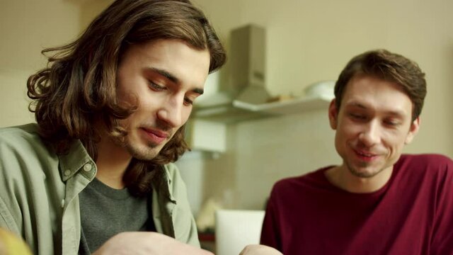 Two lovely men are cooking together and talking 
