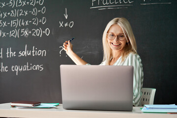 Female school college math teacher teaching online remote virtual class in classroom having video...