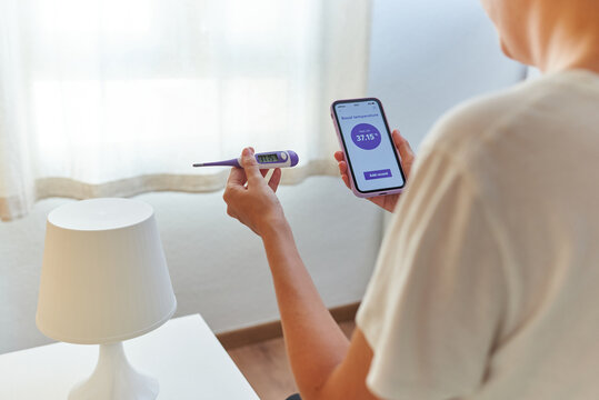 An unrecognizable woman writes down her basal temperature on her smartphone app