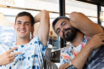 Spanish friends with patterned shirt raising arm at the bar