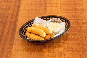 tray of Venezuelan tequeños stuffed with cheese with avocado sauce with mayonnaise on wooden table