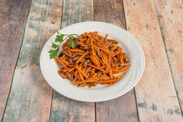 Chinese Recipe for Spicy Beef Strips Stir Fry with Carrot Strips with Fresh Parsley on White Plate