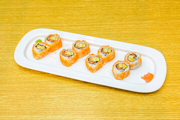 sushi uramaki california roll with masago roe, ripe avocado, nori seaweed, nori salmon and wasabi and ginseng on wooden tray