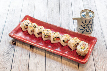 Uramaki sushi stuffed with nori seaweed, cheese, marinated salmon, ripe avocado and sesame seeds with soy sauce