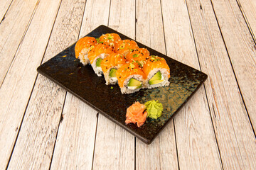 uramaki sushi roll topped with Norwegian salmon and stuffed with nori seaweed, cream cheese and ripe avocado with wasabi and ginseng with sesame and poppy seeds