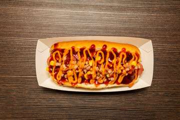 Top view image of hot dog with ketchup, fried ham tacos, sweet corn, cheddar cheese sauce inside a...