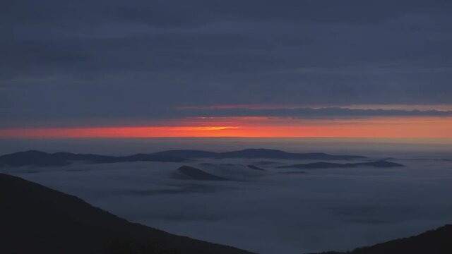 Dark inversion clouds at sunrise morning with shaky panning in Wintergreen Resort, Virginia ski town with colorful red sunlight sky in Blue ridge mountains