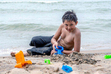 Handsome boy on the beach playing with sand toys