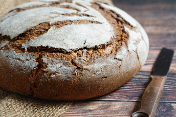 Traditional crusty bread with large round loaf. Close-up, table top.