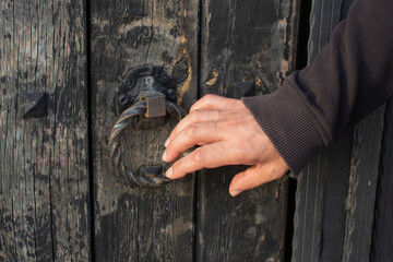 Closeup of the hand of a man knocking on an old wooden door