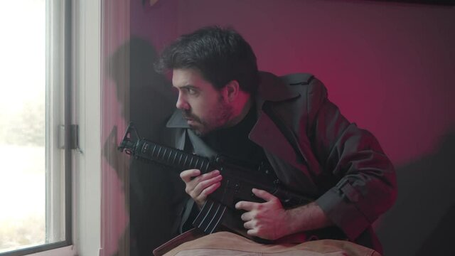 paranoid man with a gun by window