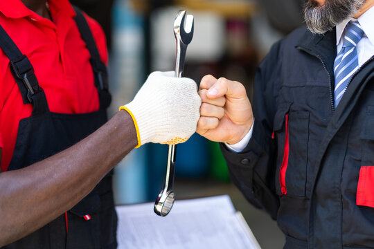 Auto mechanic with wrench in hand. stranglehold. Closeup car repair black man hand and caucasian man customer.