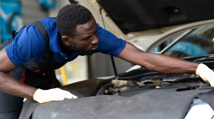 Black male mechanic repairs car in  garage. Car maintenance and auto service garage concept.