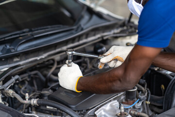 Hands Expertise car mechanic in auto repair service. Car maintenance and auto service garage concept. Black man wearing medical face mask protec virus corona