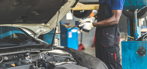 Professional car mechanic repair service and checking car engine by Diagnostics Software computer....