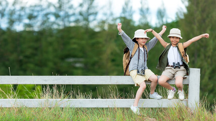 Asian two children traveler raise give me five and sitting on the white fence outdoors adventure, tourism for destination leisure trips with mountain, education explore and relax in nature park
