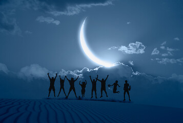 Silhouette of friends jumping on the desert with full blue crescent 