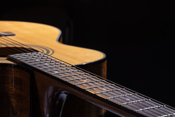 Part of acoustic guitar on black background copy space.