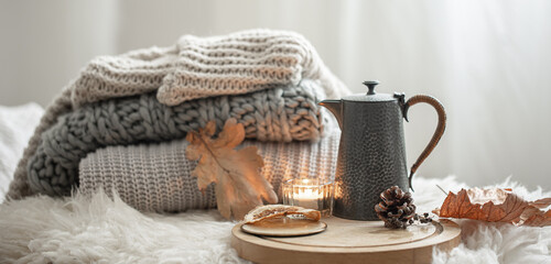 Cozy autumn composition with a stack of knitted sweaters and tea.