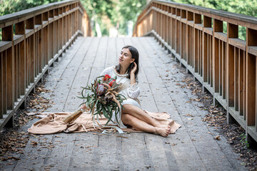 Portrait a girl in a white dress on the bridge with a bouquet of flowers.