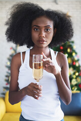 Pretty happy girl smiling while holding a glass of champagne in a Christmas party