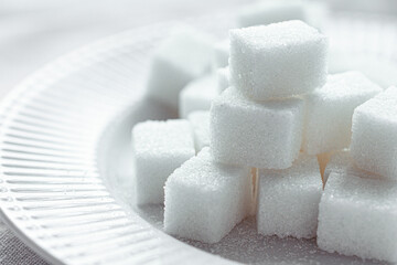 White Refined Sugar on a white porcelain plate. Selective focus, front view. Macro