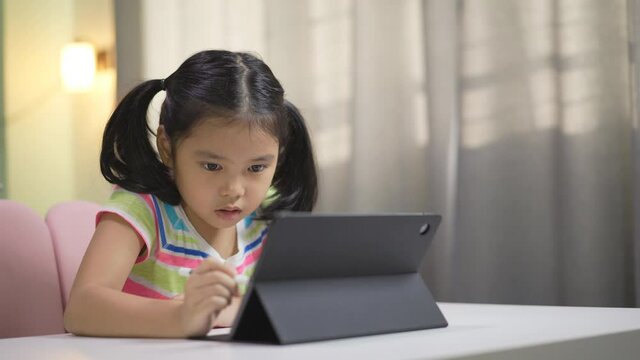 asian child student study online or kid girl enjoy write or art drawing learning on computer tablet screen by touch pen with doing homework or people back to school by learn from home on pad and warm