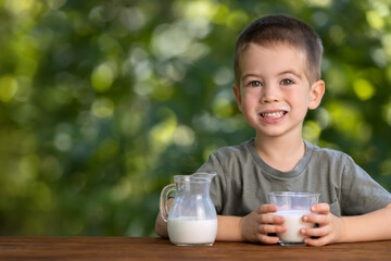 little boy with glass of milk outdoors