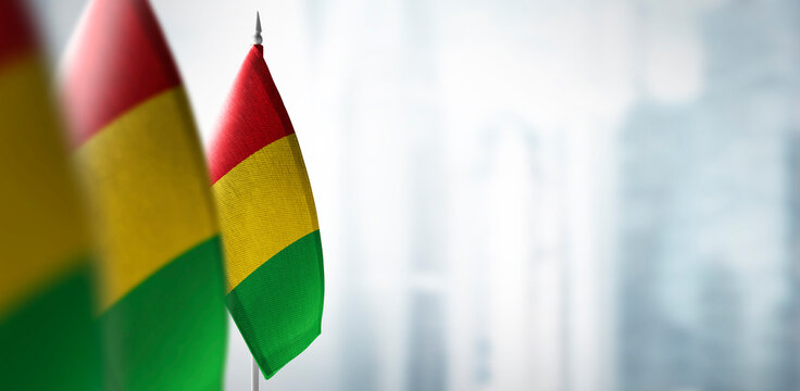 Small flags of Guinea on a blurry background of the city
