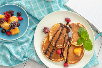 Pile of freshly cooked pancakes with blueberries on white background, morning breakfast meal