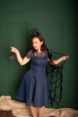 Obraz premium woman vamp on Halloween on a green background with a black lantern in her hands on Halloween, a presiding evil spirits