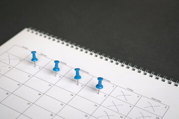 Blue pins on four days in a week on a calendar. Friday, Saturday and Sunday crossed out. Four day...