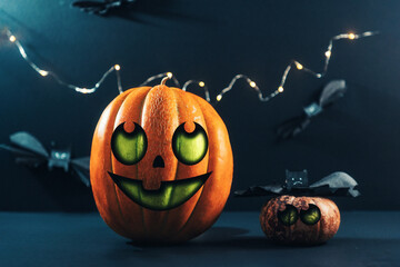 Halloween. Two colourful big and little pumpkins and paper bats. Dark background with lights. Jack's lantern decorated by childrens