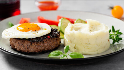 Juicy Chopped  steak with fried egg, mashed potatoes and tomato slices.