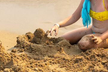 A girl sculpts buildings from sand on the beach
