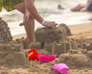 A man sculpts buildings from sand on the beach