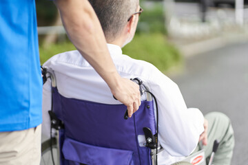 車椅子の高齢者をサポートする介護士