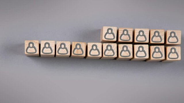Wooden blocks with black human icons being gathered in a row on gray background. Leadership, HR and Teamwork Concept. High quality 4k video