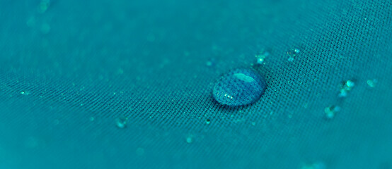Water drops on the fabric. Rain Water droplets on blue fiber waterproof fabric. Water drops pattern over a waterproof cloth. Blue background. - obrazy, fototapety, plakaty