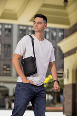 Man holding his new black leather messenger bag in a city