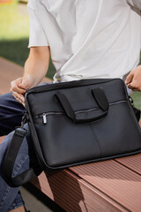Black leather bag for laptop PC closeup in male hands