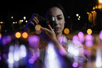 Double exposure of beautiful teenage girl taking photos in the city at night.