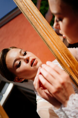 a beautiful young woman in a lace robe looks at her reflection in the mirror.