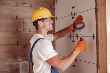 Male builder installing ceramic wall tile in house